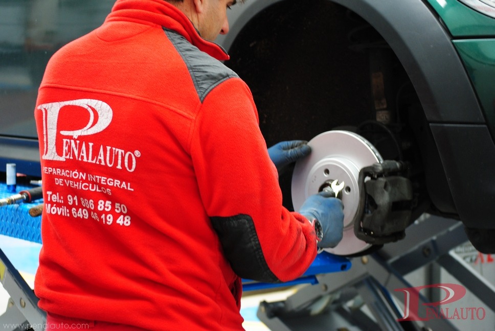Mecánico ajustando el sistema de frenos de un coche en un taller mecánico en Torres de la Alameda